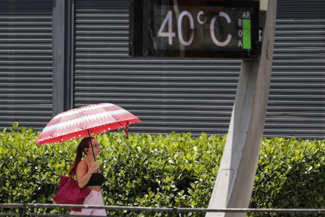 Uma jovem se protege do sol com um guarda-chuva na Avenida Paulista, onde termômetros urbanos registram temperatura de 40,0 graus Celsius na cidade de São Paulo, Brasil, 14 de novembro de 2023