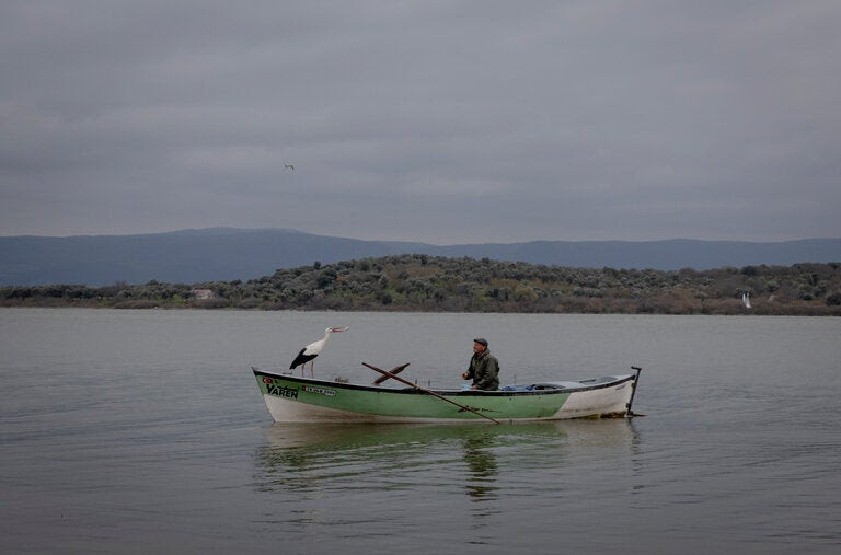Adem Yilmaz in his fishing boat with his stork companion, Yaren. 