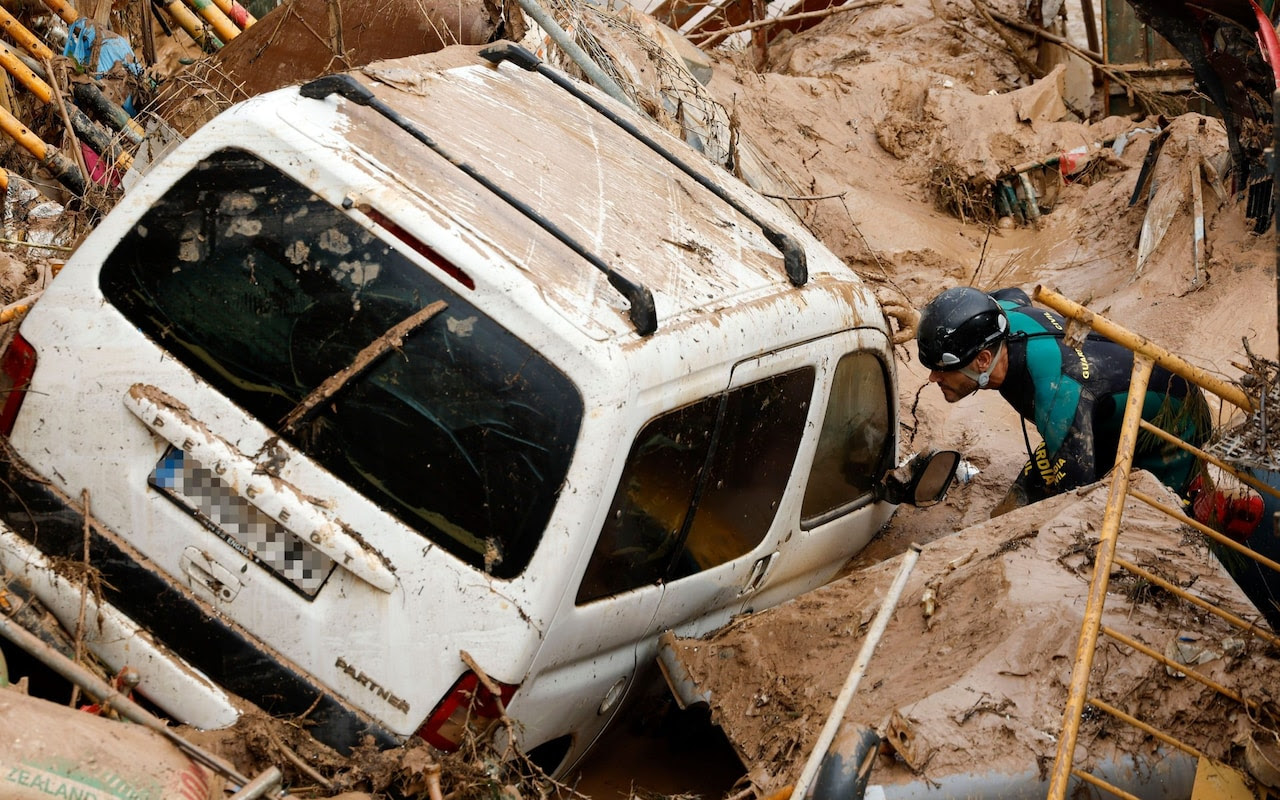 Rescuer looks inside car stuck in mud