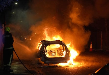 Firefighters tend to a burning police car in Hartlepool after a violent protest.