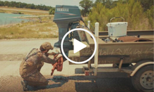 man in waders cleaning his boat motor, video link