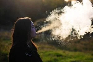 woman exhaling smoke or vape steam