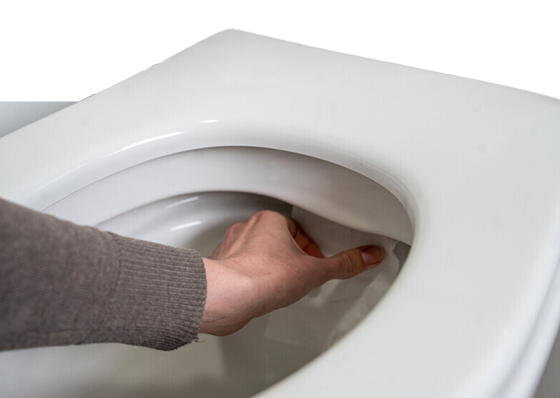 A person checking the back of a toilet basin for leaks