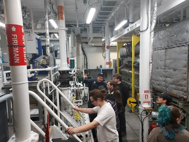 Several people in the engine room of a ferry