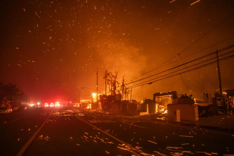 Palisades Fire burns homes along a highway, and the wind burns orange embers toward the photoagrapher