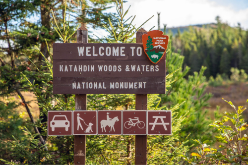 A brown wooden sign: Welcome to Katahdin Woods & Waters NM.