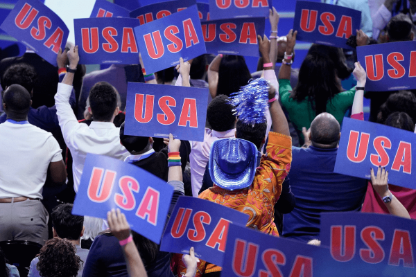 Back of a crowd holding up blue and red signs that say 