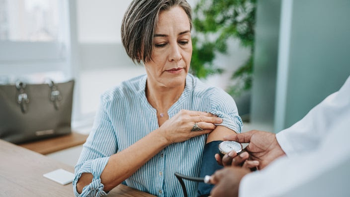 A woman gets her blood pressure measured by a healthcare professional.