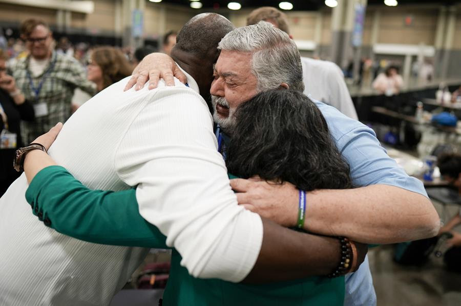 Three people embrace at the United Methodist Church's legislative conference.