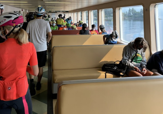 Several bicyclists with helmets on in the passenger cabin of a ferry