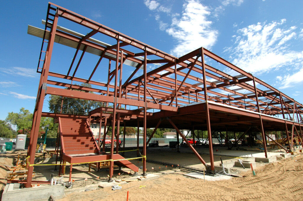 A steel framed building being constructed with a staircase in the ground