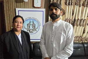 Zimran Asim is standing with his lawyer. There is a poster behind them which reads, "[Stand] up for your rights. The Voice Society." 