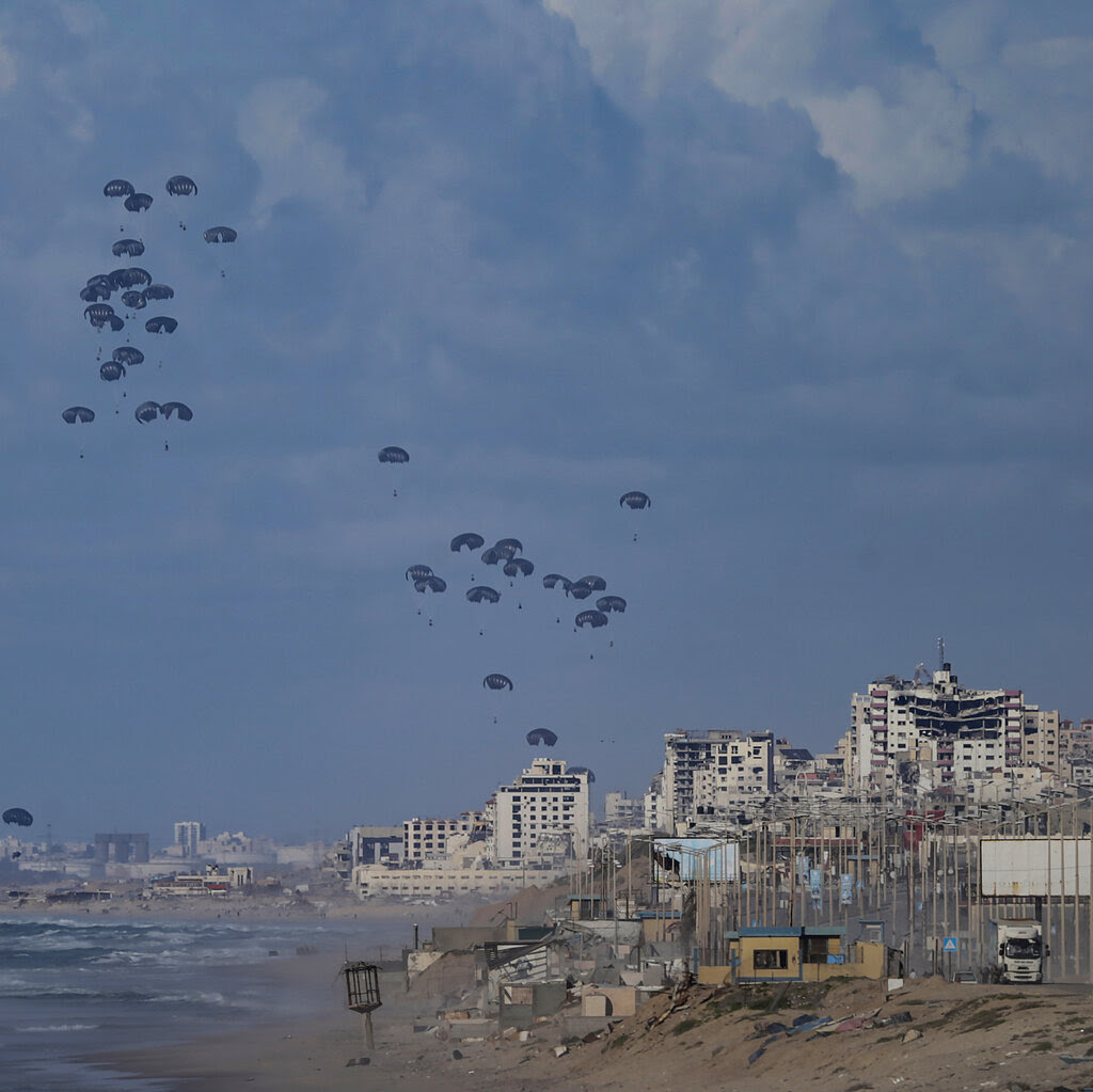 Dozens of U.S. aid packages attached to parachutes drift down over Gaza.