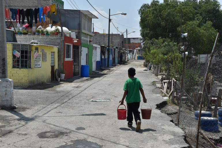 A boy carries home buckets filled from barrels of drinking water loaded from tanker trucks in the Mexico City borough of Iztapalapa on April 19, 2017. Dozens of municipal tanker trucks in Mexico City distribute water in neighborhoods that do not receive piped water. In Iztapalapa approximately two million people have no running water and have to fill barrels and carry it to their homes in buckets. (Photo by YURI CORTEZ / AFP) / TO GO WITH AFP STORY BY YUSSEL GONZALEZ - TO GO WITH AFP STORY BY YUSSEL GONZALEZ