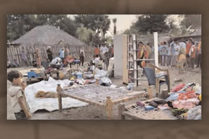 Furniture and other possessions are strewn across the ground. Several people are gathered around, observing the mess.