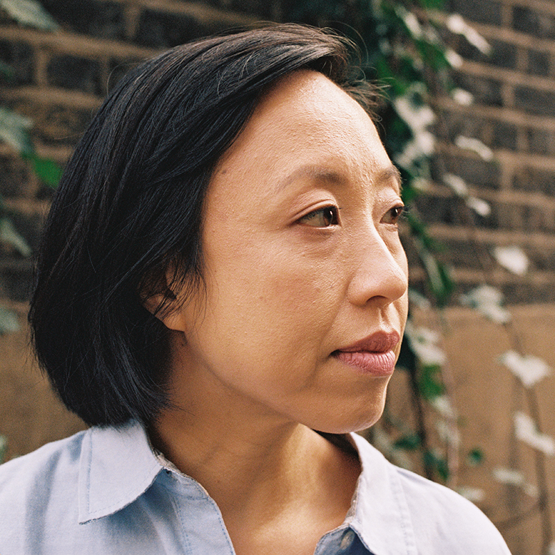 A woman looks away from the camera with a pensive expression.