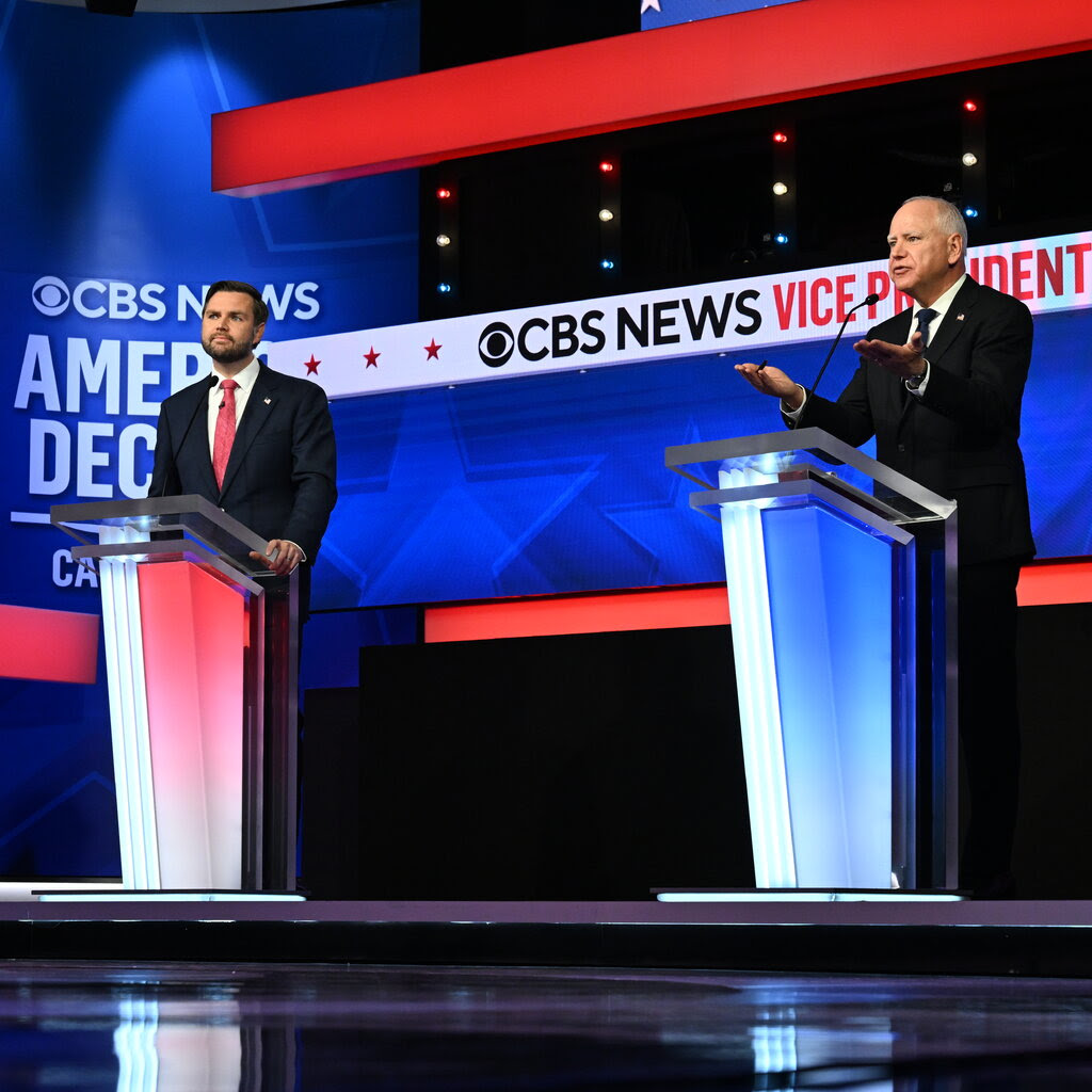 JD Vance and Tim Walz, both wearing suits, on a debate stage.