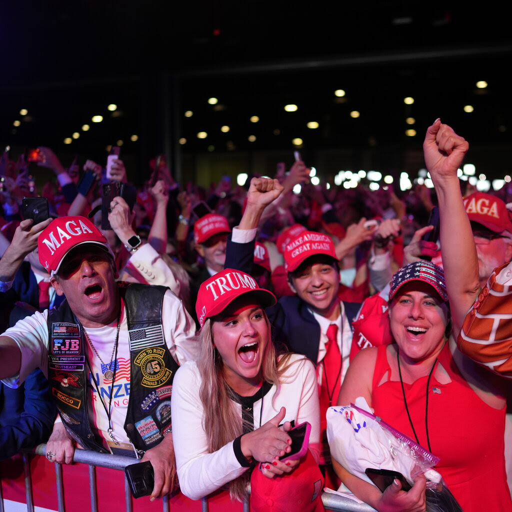 People cheering wearing Trump hats. 