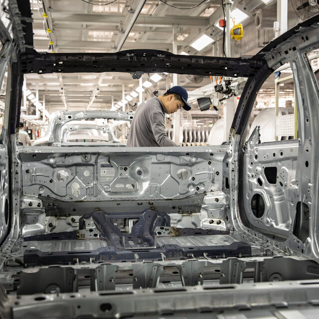 Looking through the window of a car, on the production line at person in a car factory.