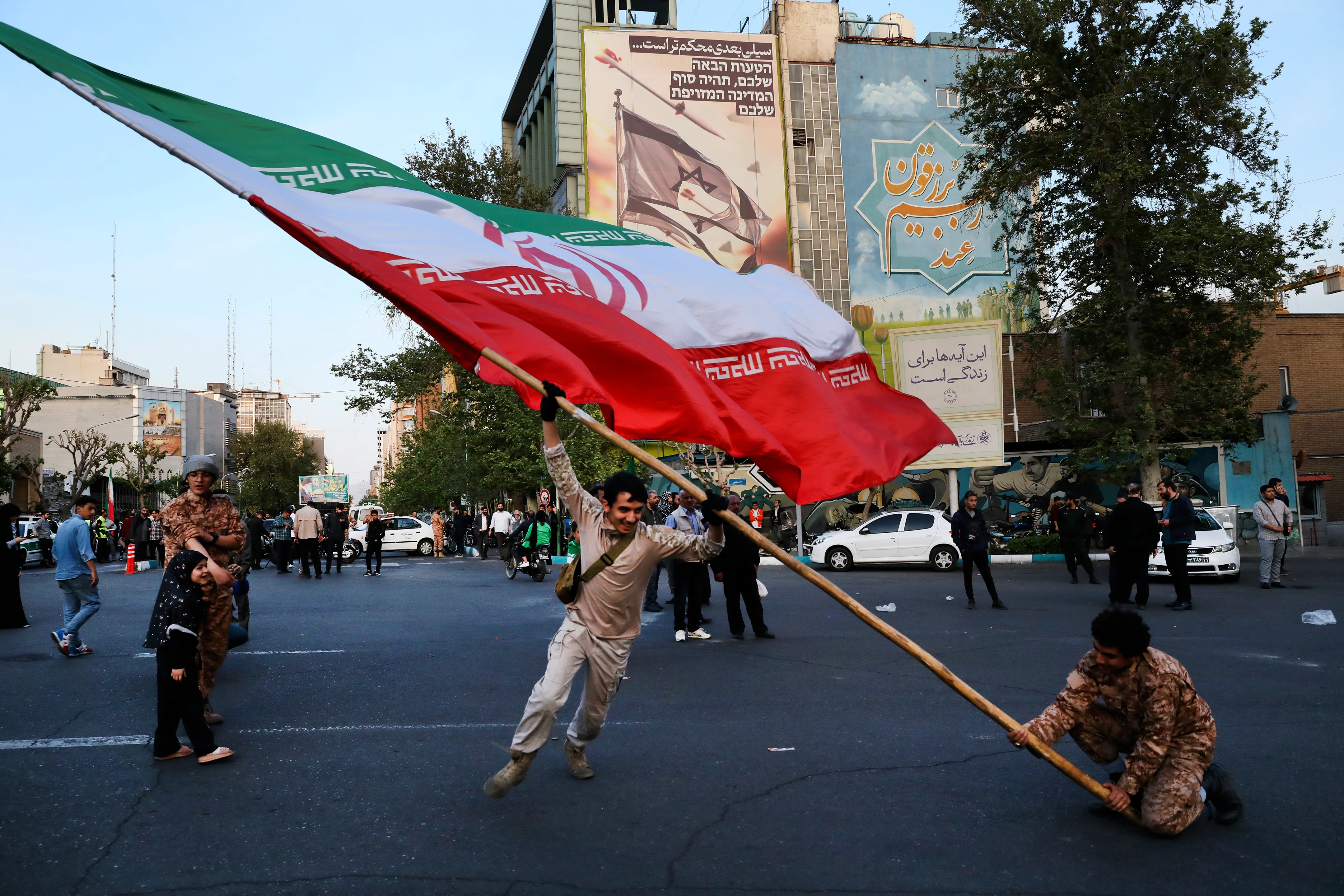 Demonstrators wave a huge Iranian flag in their anti-Israeli gathering in front of an anti-Israeli banner on the wall of a building in Tehran, Iran on Monday.