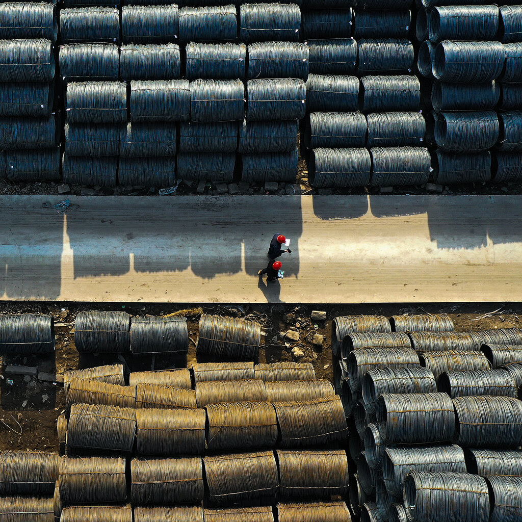 An aerial scene of two people walking through a steel market. 