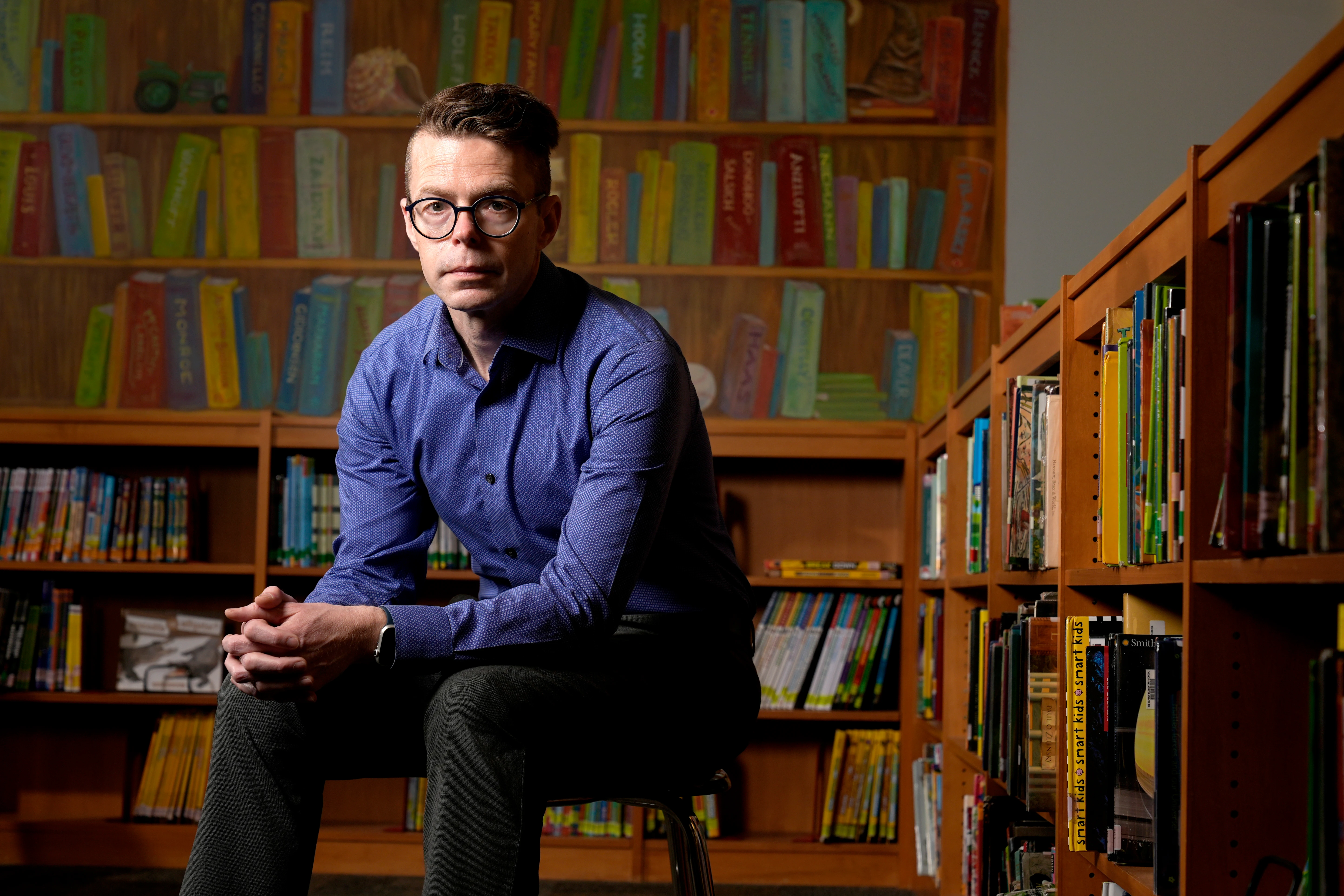 Tom Bober, librarian and President of the Missouri Association of School Librarians, sits in front of a wall of books.