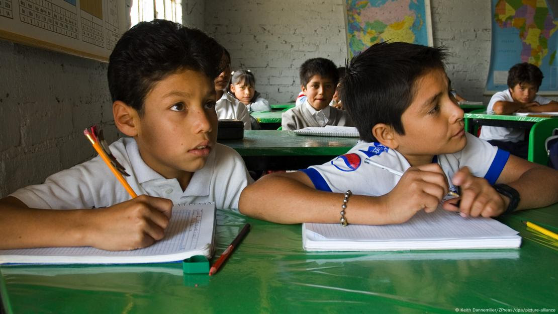Dois meninos em uma sala de aula no México com alguns outros estudantes atrás deles