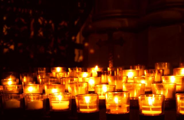 Votive candles lit in the darkness