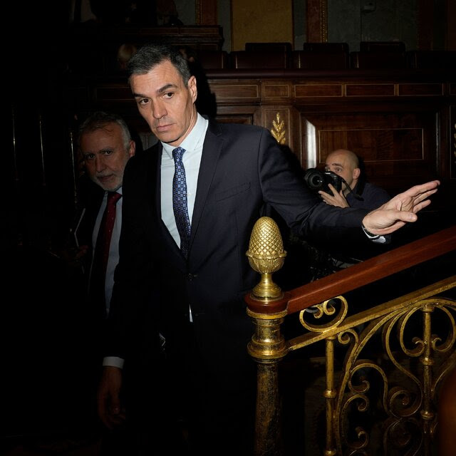 Pedro Sanchez descending a staircase into a dark room in Spain’s Parliament.
