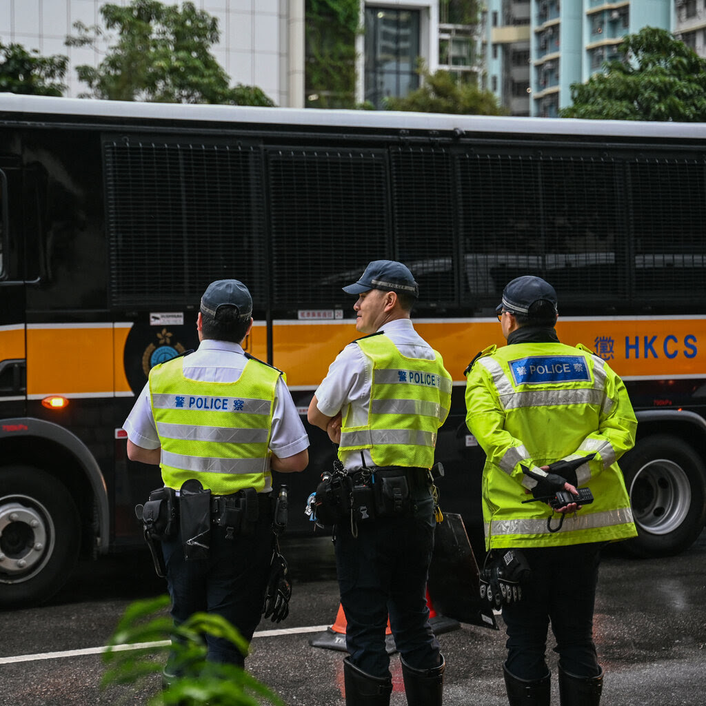 Three police officers in front of a van with barred windows.