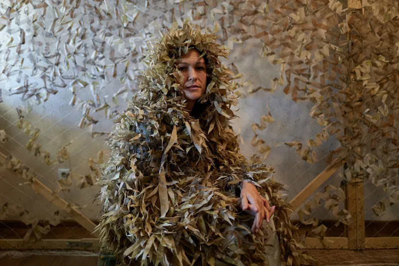 Olya, a member of the Gang of Angels, a volunteer group that makes camouflage netting for Ukraine’s military, poses with a sniper camouflage net in Odesa, Ukraine, on Oct. 13. Soldiers send photos of their surroundings, and the volunteers select fabric colors to match their environment.