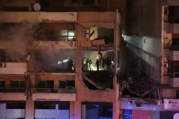 A badly damaged building. People can be seen standing inside.