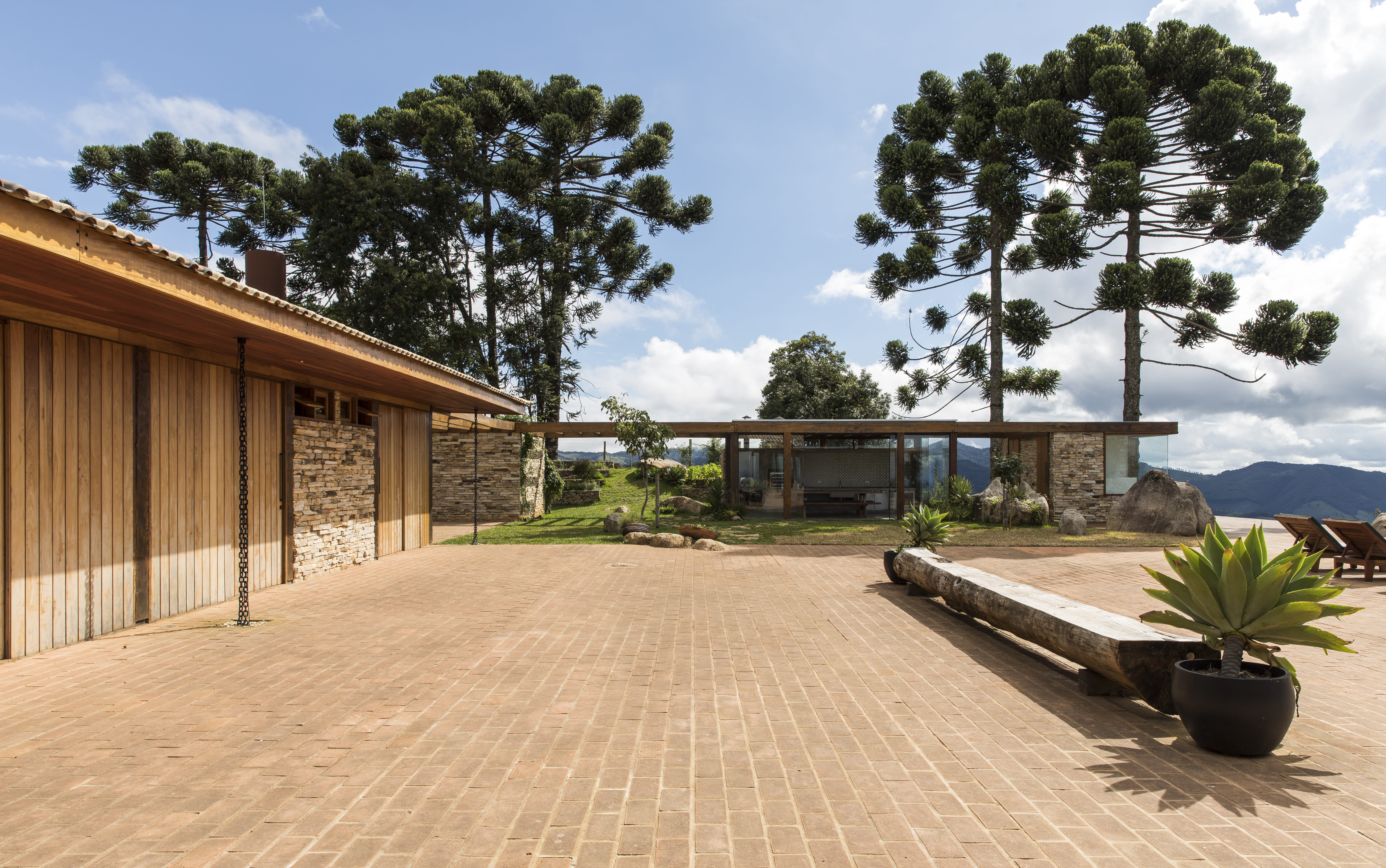 Um caminho sinuoso pela montanha revela gradualmente a casa de veraneio, com inspiração balinesa que lembra a infância do arquiteto Frederico Sabella. A entrada abaixo conduz à garagem, protegida por uma pérgula verdejante e também é fácil o acesso direto às suítes e ao espaço social | Projeto Sabella Arquitetura | Fotos: Maíra Acayaba 