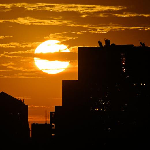 (FILES) The sun rises behind high-rise buildings in Beijing on September 6, 2024. 2024 was China's warmest on record, its weather agency said, as the world experiences a surge in extreme weather fuelled by climate change. (Photo by ADEK BERRY / AFP)