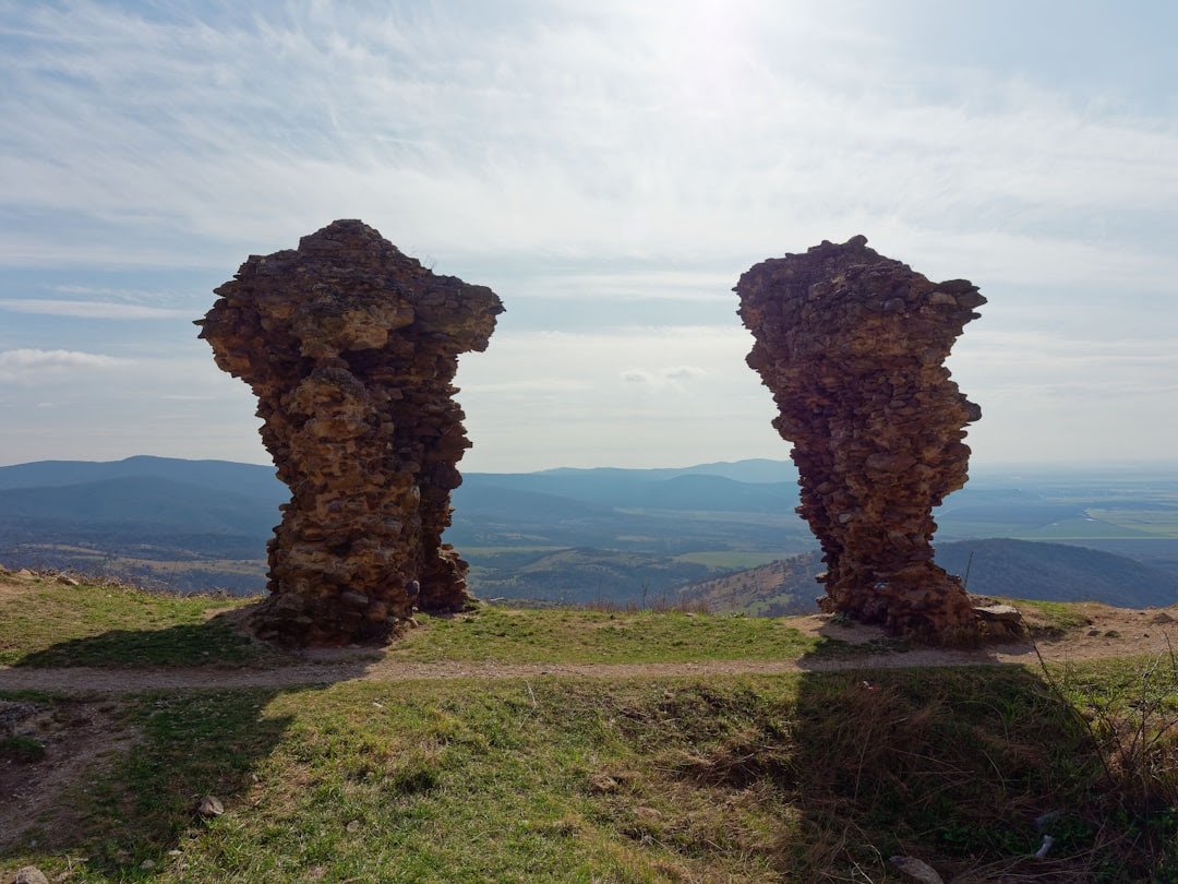 a couple of large rocks sitting on top of a grass covered hillside