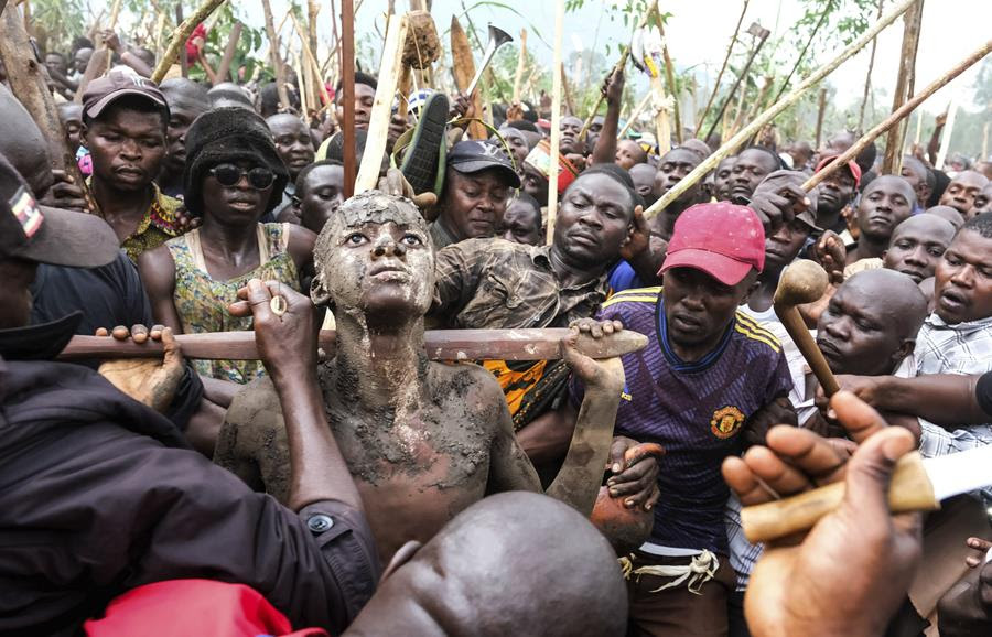 A crowd surrounds a young boy participating in the Imbalu ritual.