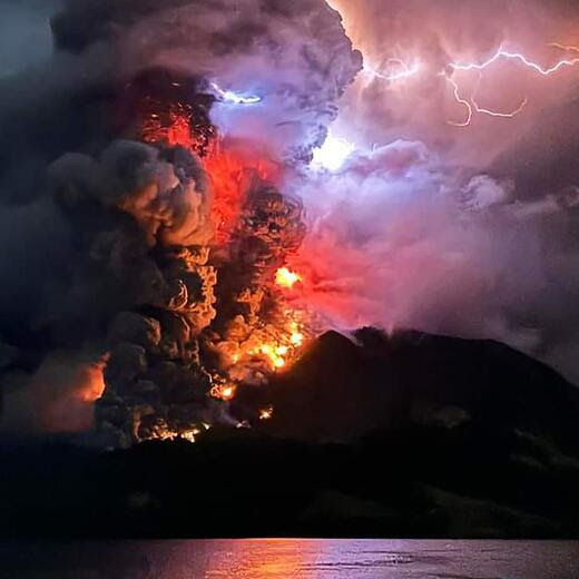 This handout photograph taken and released by the Center for Volcanology and Geological Hazard Mitigation on April 17, 2024, shows Mount Ruang spewing hot lava and smoke as seen from Sitaro, North Sulawesi. A volcano erupted several times in Indonesia's outermost region overnight on April 17, forcing hundreds of people to be evacuated after it spewed lava and a column of smoke more than a mile into the sky. (Photo by Handout / Center for Volcanology and Geological Hazard Mitigation / AFP) / RESTRICTED TO EDITORIAL USE - MANDATORY CREDIT AFP PHOTO / CENTER FOR VOLCANOLOGY AND GEOLOGICAL HAZARD MITIGATION/ PVMBK - NO MARKETING - NO ADVERTISING CAMPAIGNS- DISTRIBUTED AS A SERVICE TO CLIENTS