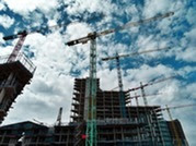 Construction project with multiple cranes looking at a cloudy sky from below