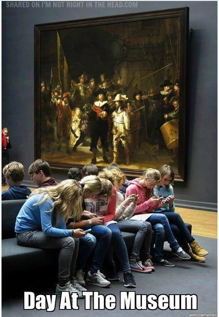 Photo of kids at museum looking at their phones.