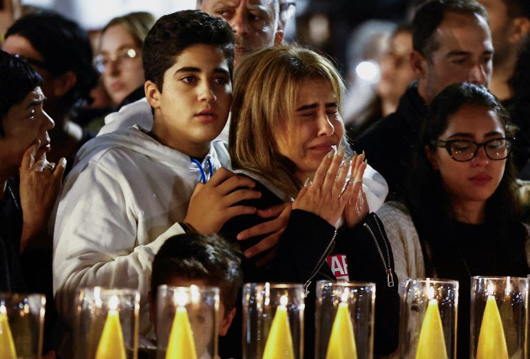 People react as they stand near a set of candles lit for the Israeli hostages who are being held in the Gaza Strip after they were seized by Hamas gunmen on October 7, as the country observes the Jewish festival Hanukkah amid the ongoing conflict between Israel and the Palestinian Islamist group Hamas, in Tel Aviv, Israel December 7, 2023. REUTERS/Clodagh Kilcoyne