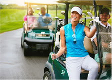 A woman exiting a golf cart smiles along side a man driving the golf cart.