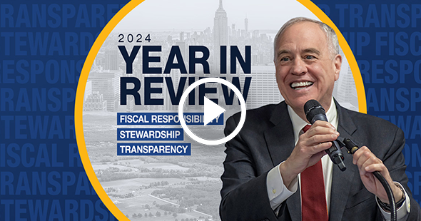 New York State Comptroller Thomas P. DiNapoli holding a microphone and smiling.