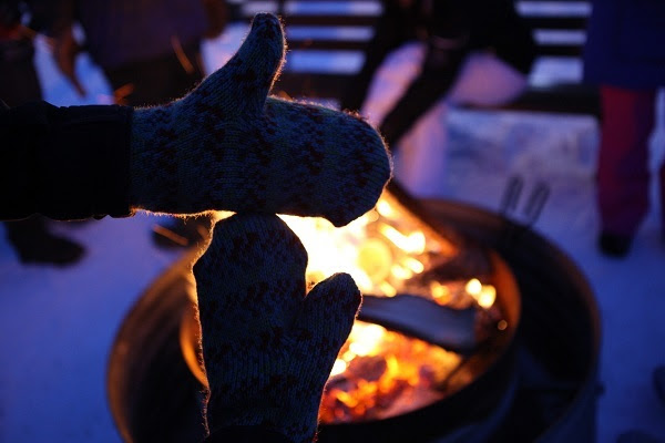 Shadowed outline of mitten hands forming Michigan's two peninsulas, backlit by a crackling orange campfire 