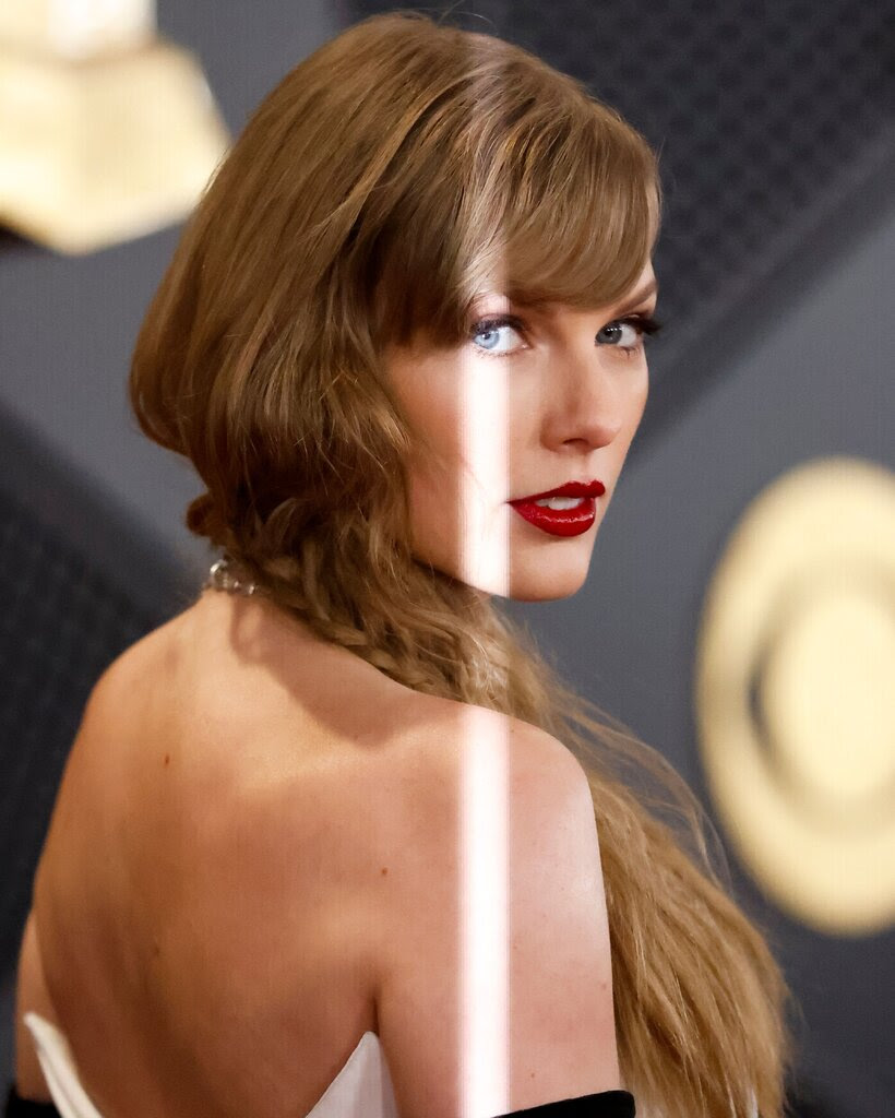 Taylor Swift wearing red lipstick in a strapless dress looks at the camera over her shoulder.