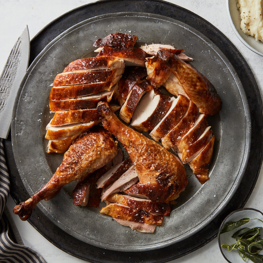 A plate of carved roast turkey, its skin dark golden brown and scattered with salt.