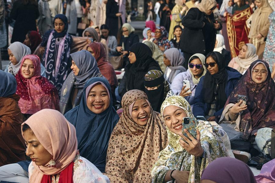 Muslim women smile and pose for selfies as they gather for an Eid al-Fitr prayer.