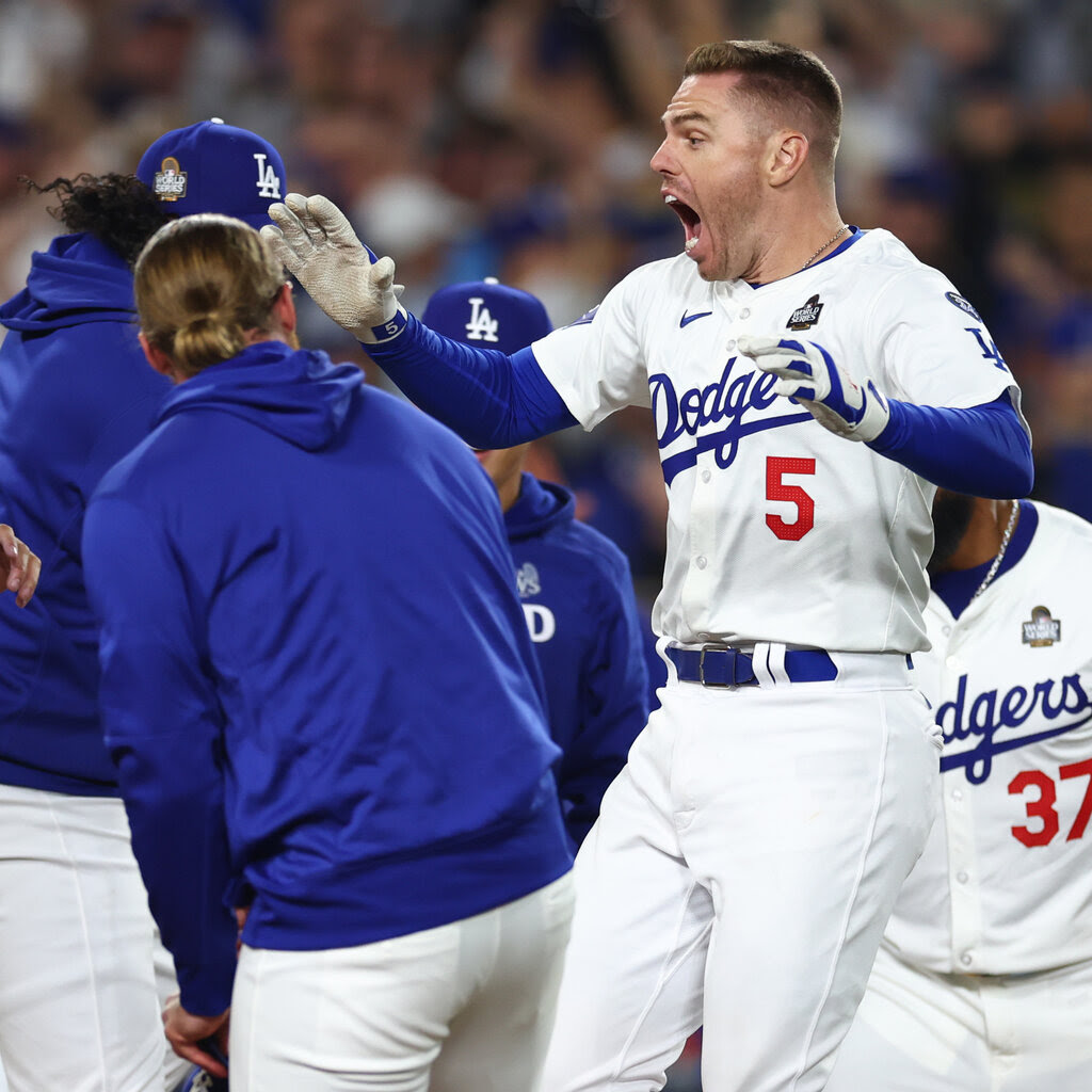 Freddie Freeman of the Dodgers jumps and screams in celebration, surrounded by teammtes.