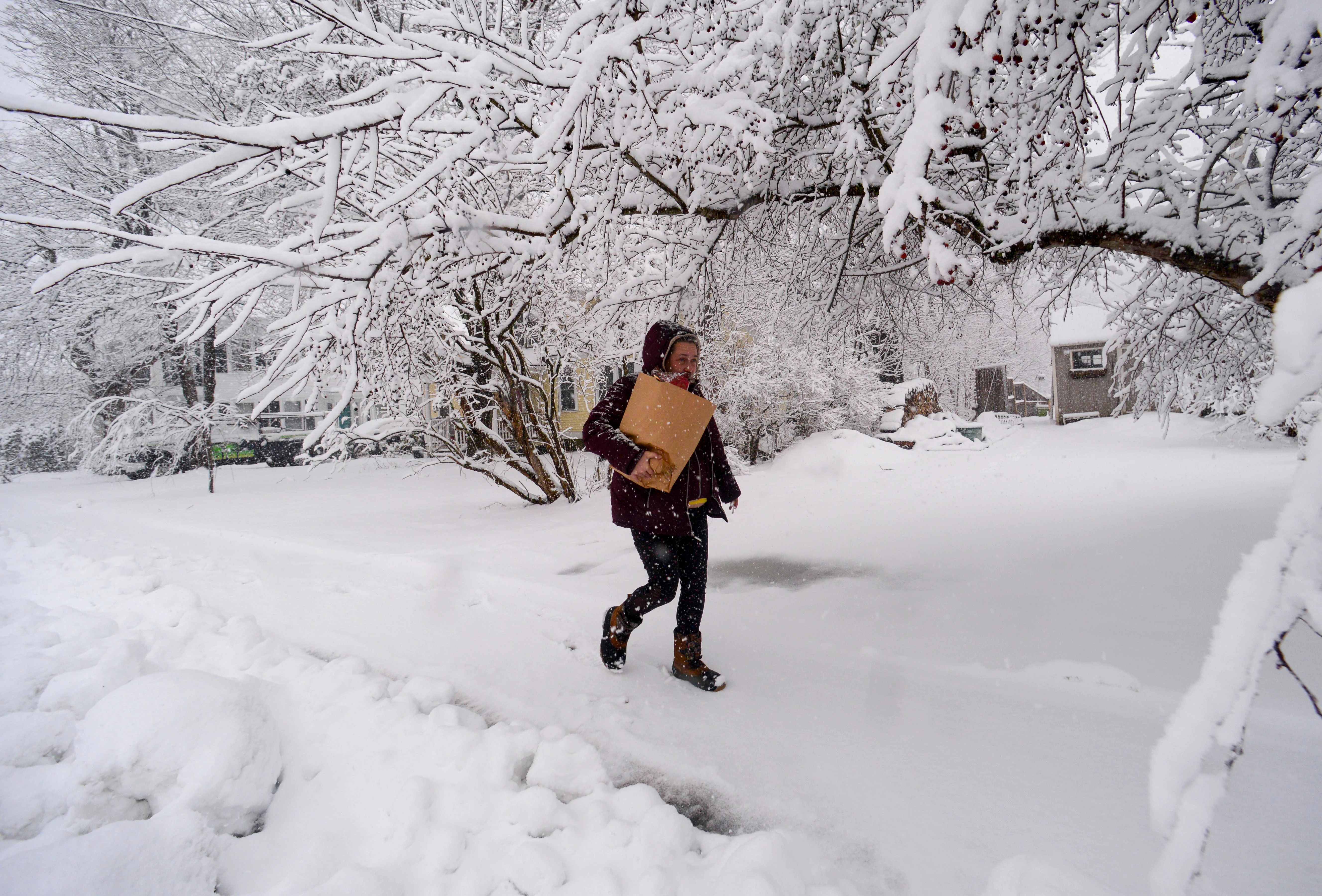 Amber Morin of Saxtons River, Vt., carries a bag of groceries in the snow after visiting the local market.