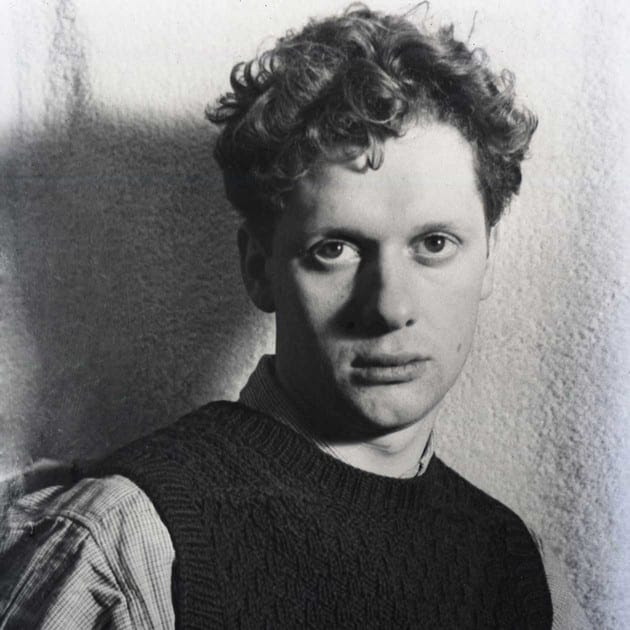 A black-and-white photo of a young Dylan Thomas wearing a dark woollen sweater vest and staring at the camera with an ambiguously blank expression.