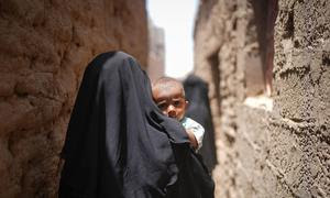 Una madre camina con su hijo en brazos por el barrio Al Adani de Al Hawtah, Gobernación de Lahj, Yemen.